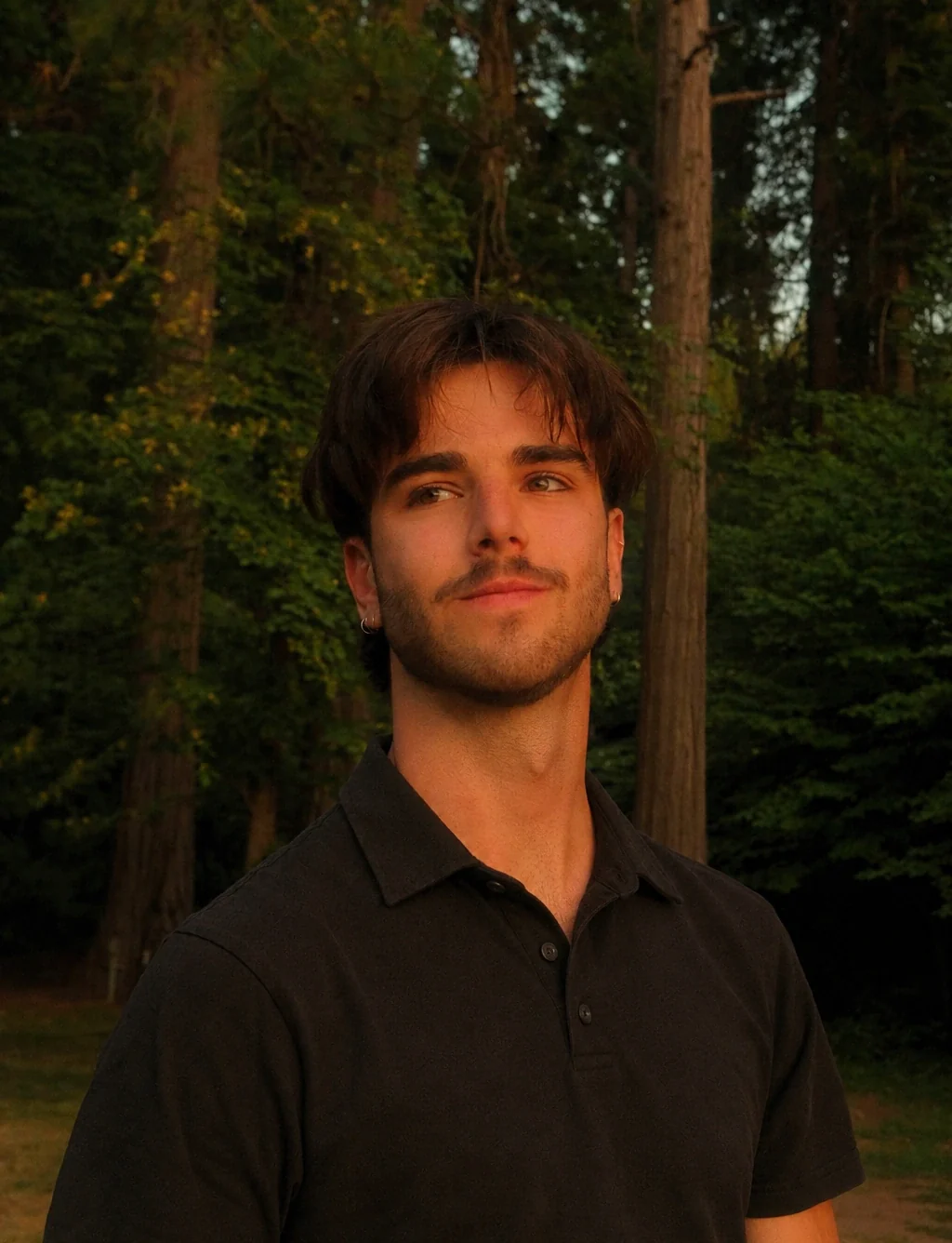 Casey Van Wandelen, founder of Good Mischief, wearing a black collared shirt in a sunlit forest.